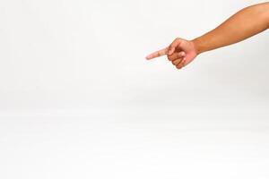 A brown-skinned arm and hand points to the left against a white background, highlighting a specific location or direction photo