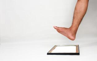 Concept of stepping over boundaries or limits, represented by foot about to step on picture frame photo