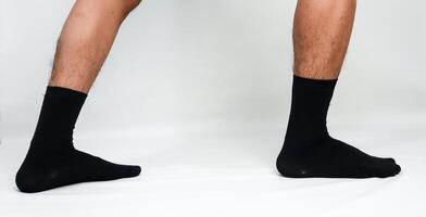 Close-up studio shot capturing a person's legs and feet wearing stylish black socks on white background photo