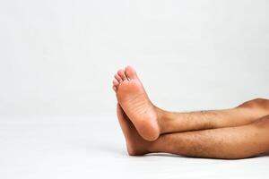 Close-up of a man's bare feet crossed against a white background in a studio setting providing ample copy space for creative use photo