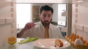 POV refrigerator point of view from inside fridge with one egg lettuce half lemon Caucasian confused man adult male guy take empty bottle of orange juice eat bread crumbs food delivery supermarket video