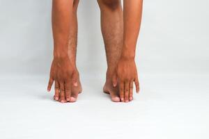 Close-up of a Man Touching His Toes Stretching Against a White Background, demonstrating Flexibility and a healthy Lifestyle photo