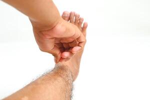 Close-up of a Person Examining or Inspecting Their Foot with Hand on a White Background photo