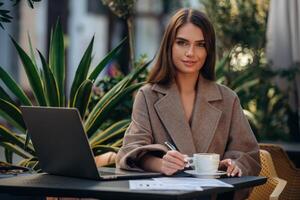 Woman working on laptop outdoors photo