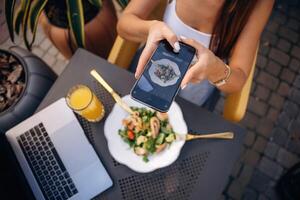 Making ,a ,photo of food. Beautiful young woman is outdoors of the restaurant by the table photo