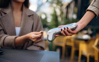 Woman, is paying for food in cafe by using credit card. Conception of wireless money transfer photo