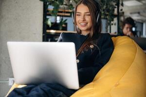 Woman is sitting and working by using laptop photo