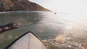 First-person view of surfing. Surfer rowing on surfboard in ocean. video