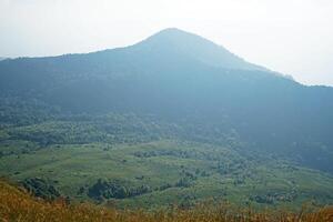 Natural top landscape of green mountain summit range with cloudy white sky photo