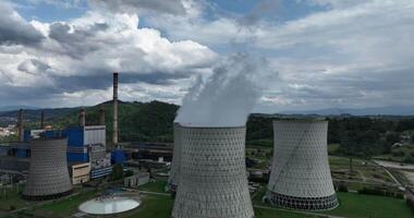 Aerial drone footage of a large coal power plant station with cooling towers chimney and boiler house in an air pollution or carbon footprint concept video