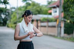 Young woman using a smartwatch while exercising outdoors in a suburban area, focusing on fitness and technology. photo