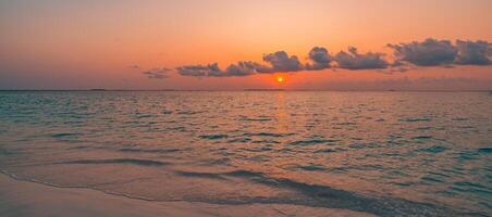 Sunset beach closeup featuring gentle sea waves, warm sand, and dramatic sky colors, tranquil tropical shore landscape inspiring dreamy travel, summer getaway, and nature escape photo