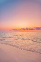 Vertical closeup of sunset beach with golden sand, calm sea waves, vibrant colorful sky, serene tropical landscape, peaceful nature scene perfect for travel, vacation, and relaxation vibes photo