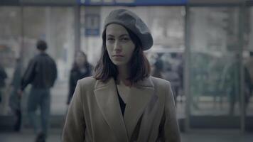 Stylish woman in a beret waits calmly at a busy train station, showing elegance in the crowd video