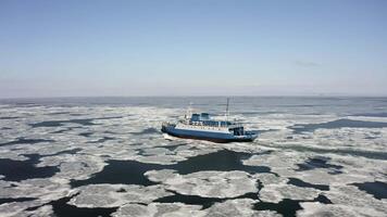 A ferry among ice floes on a sunny day in winter from a drone video