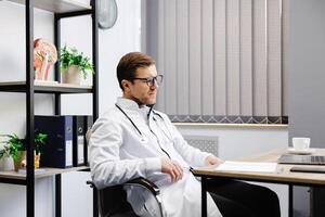 Doctor sits at his workplace and feels tired from work. A doctor takes a break from his work day because of pain photo