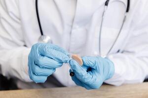 An otolaryngologist holds a hearing aid in his hands. The doctor consults the patient photo