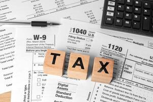 Tax season concept with wooden letter blocks, calculator, and pen on 1040 tax form. Income tax filing and financial planning background photo