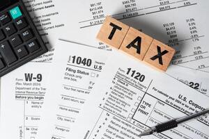 Tax season with wooden alphabet blocks, calculator, pen, on 1040 tax form background photo