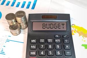 A calculator with the word BUDGET on the display, with coins and business documents photo