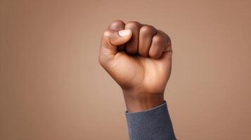 A clenched fist held up in a gesture of empowerment Symbolizes strength and solidarity Focus on human hand against a warm-toned background photo