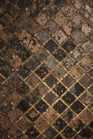 Close-up of vintage diamond-patterned tiles with bronze grouting. Texture and aged details visible. photo
