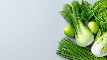 A fresh collection of green vegetables and fruits arranged on a plain background Healthy natural produce ready to be prepared and enjoyed photo
