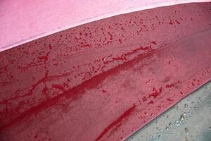Raspberry red color surface of wet umbrella closeup with water drops photo
