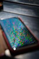Bright rainbow rays reflect in mobile phone screen surface with dark blurred background. Multicolored beams and reflection in smartphone screen closeup photo