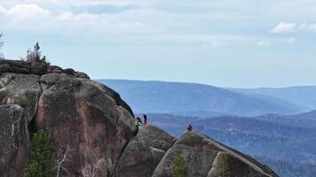 Adventure seekers climb rocky terrain in scenic mountain region during daytime video