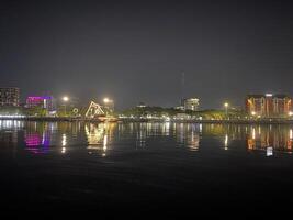 City lights shimmer and reflect on the tranquil water at night creating a peaceful scene. photo