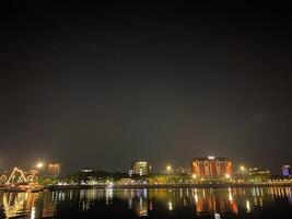 City lights reflect on the water creating a vibrant and captivating nighttime urban scene. photo