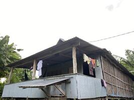 Rustic dwelling stands amidst lush greenery with laundry drying in the tropical air. photo