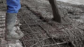 A Construction Worker is pouring concrete meticulously onto a carefully prepared rebar framework. Clip video