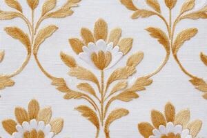 Intricate jaal pattern featuring floral motifs in golden hues on a textured white fabric, showcasing elegance and traditional craftsmanship in textile design photo