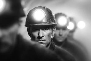 Group of miners wearing helmets with headlamps, focused expressions, walking through a dimly lit tunnel, showcasing teamwork and determination in a challenging environment photo