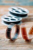 Film reels and strips of photographic film are arranged on a rustic wooden surface, showcasing the texture and details of vintage cinematic materials and their nostalgic appeal photo