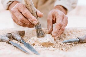 Skilled artisan using a brush to refine a stone sculpture, surrounded by carving tools, showcasing the intricate details of stonework and craftsmanship in a creative workspace photo
