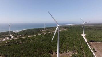 Wind turbine rotating and generating renewable energy on a sunny day, with the ocean in the background video