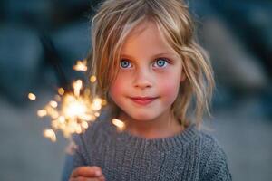 Young girl with sparkling eyes holds a sparkler, wearing a cozy gray sweater, surrounded by a soft, blurred background, capturing the joy of celebration and wonder in a festive atmosphere photo