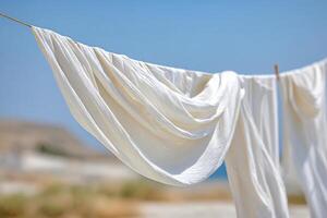 Flowing white fabric draped elegantly on a clothesline against a serene outdoor backdrop, capturing the essence of tranquility and natural beauty in a sunlit environment photo