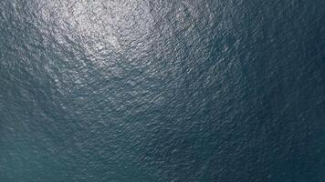 Sunlight reflects on a deep blue water surface, creating a shimmering effect with small waves dancing across the scene video