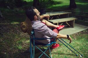 Man Relaxing Outdoors in a Forest Environment Near a Wooden Picnic Table photo