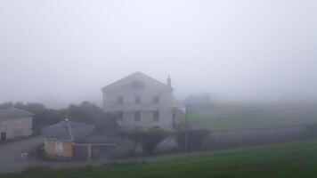 Fog gradually envelops a large, old house in the countryside, creating a mysterious and atmospheric scene video