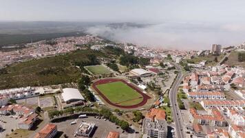 Low clouds move toward a coastal city featuring a stadium, creating a dramatic sky over the urban landscape video