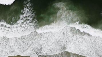 Ocean waves crashing against a sandy beach create a stunning scene filled with white foam and vibrant blue waters video