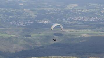 Paraglider is soaring over a beautiful valley, enjoying the breathtaking views of the mountains and countryside below video