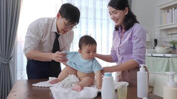A tiny child happily on the towel waiting for parents apply powder and put on clothes after taking a bath video