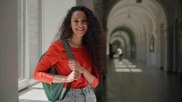 Happy smiling friendly Hispanic woman Latina girl student female in university college academy hall corridor invite join to education inviting to studying welcome come here gesture welcoming learning video