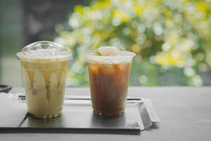 Close up glass of ice black coffee with lychee juice and ice cappucino on raw cement table of a coffee shop summer terrace, menu photography photo